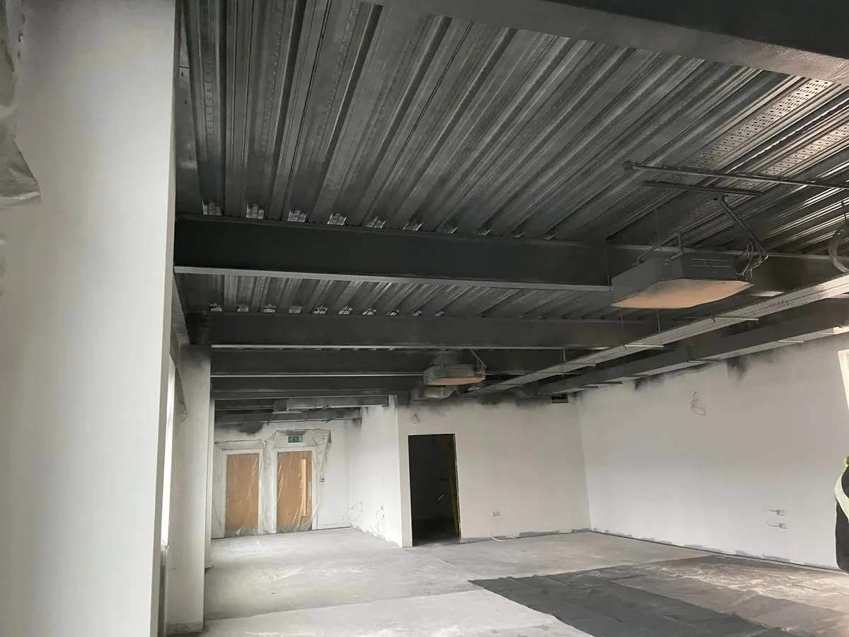 Commercial corridor with freshly painted ceiling steelwork and white walls