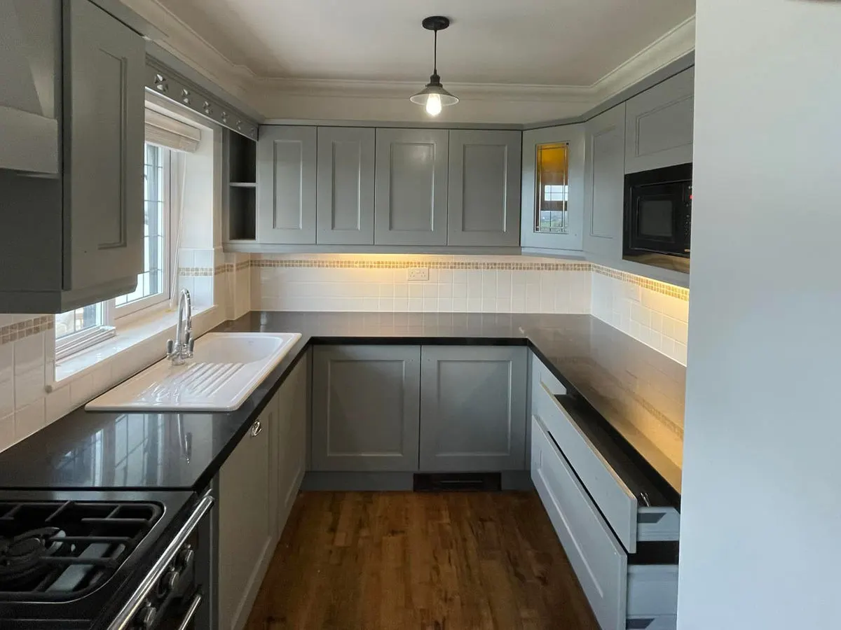 U-shaped kitchen with grey sprayed shaker cabinets black granite worktops and under-cabinet lighting