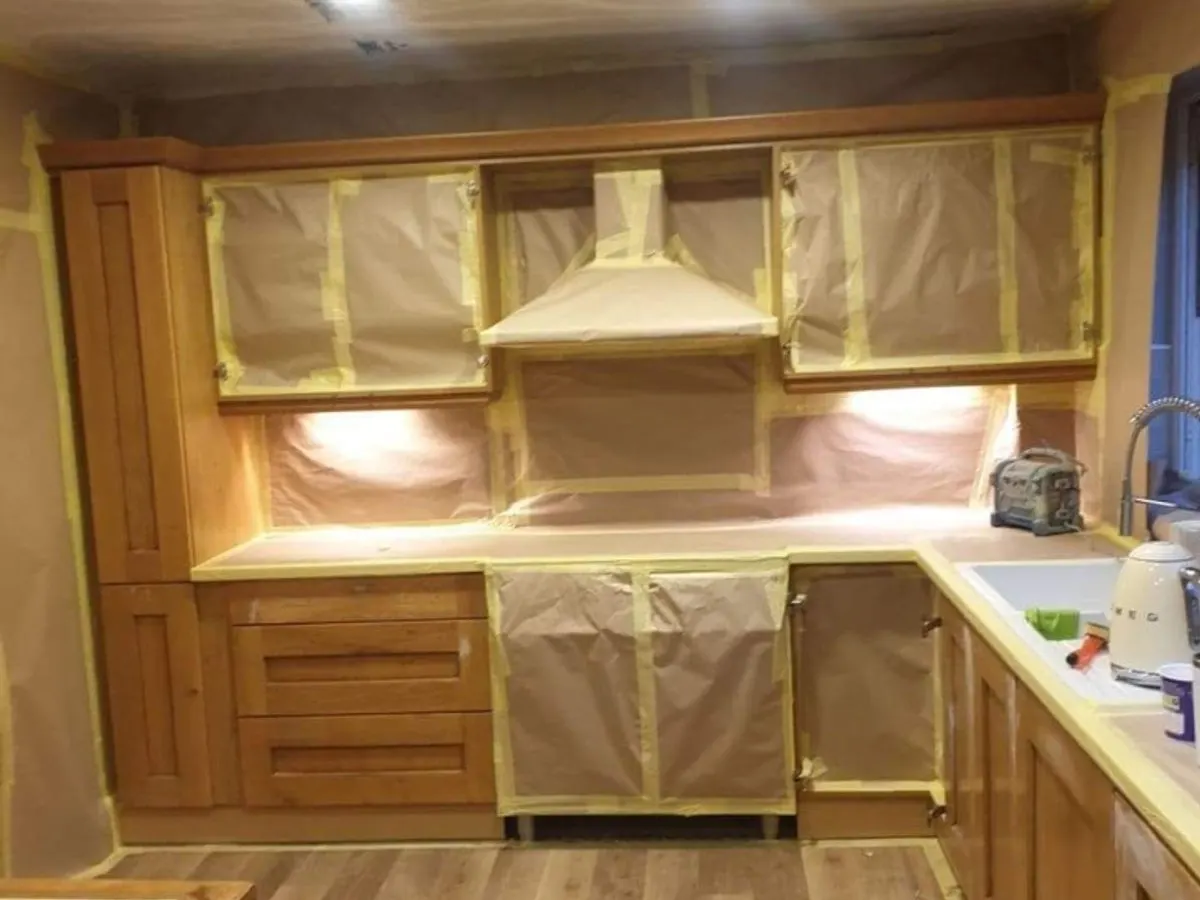 Oak kitchen fully masked with protective paper and tape ready for spray painting transformation