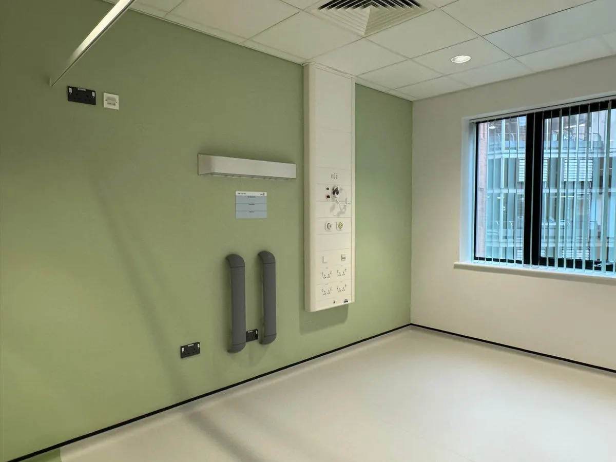 Hospital patient room with calming green painted walls medical service panel and window
