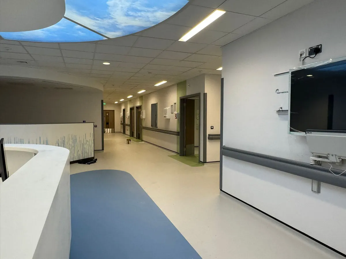 Newly painted hospital ward corridor with blue accent flooring sky ceiling feature and nurses station