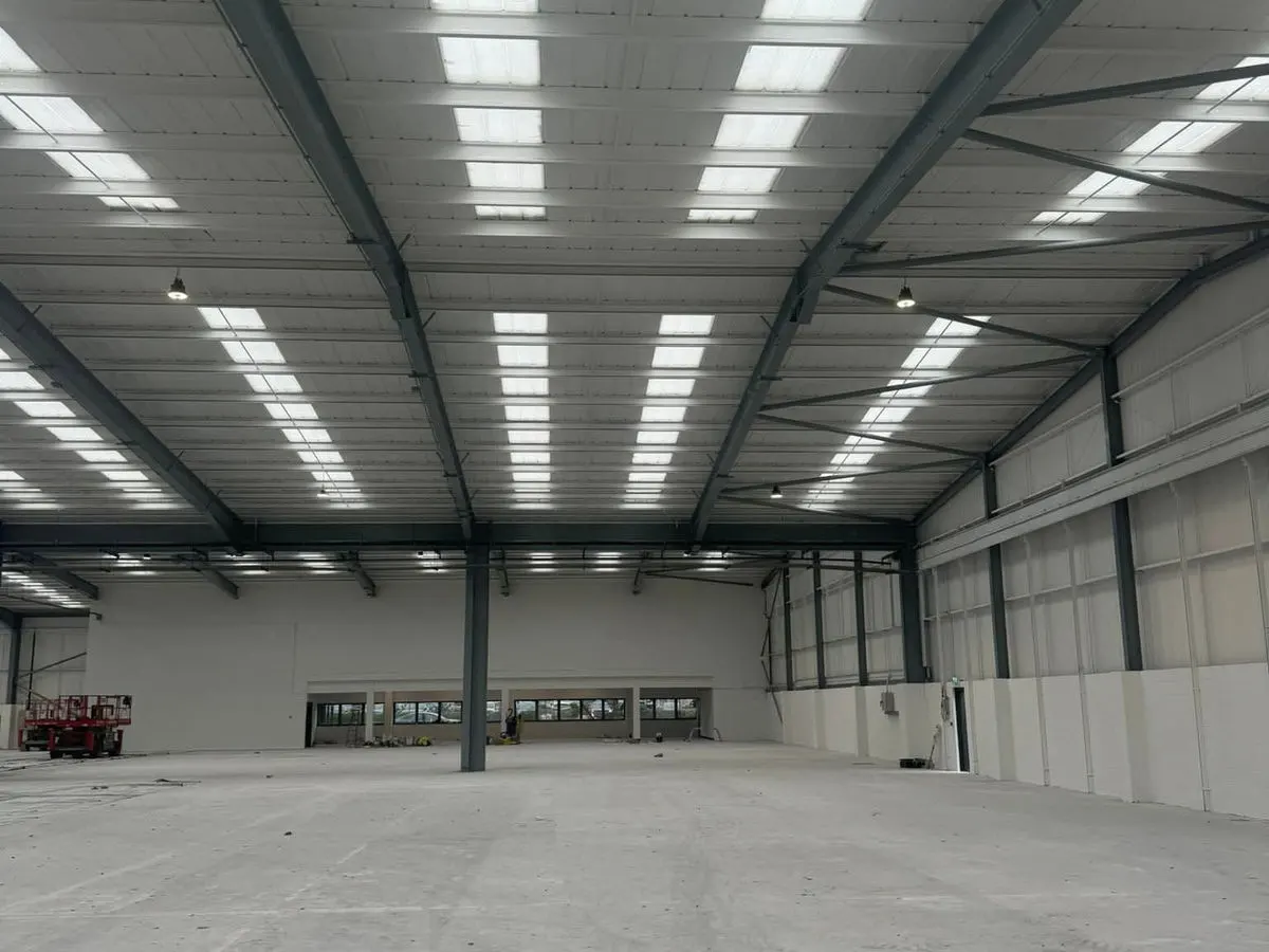 Large industrial warehouse interior freshly painted white with steel beam structure and skylights