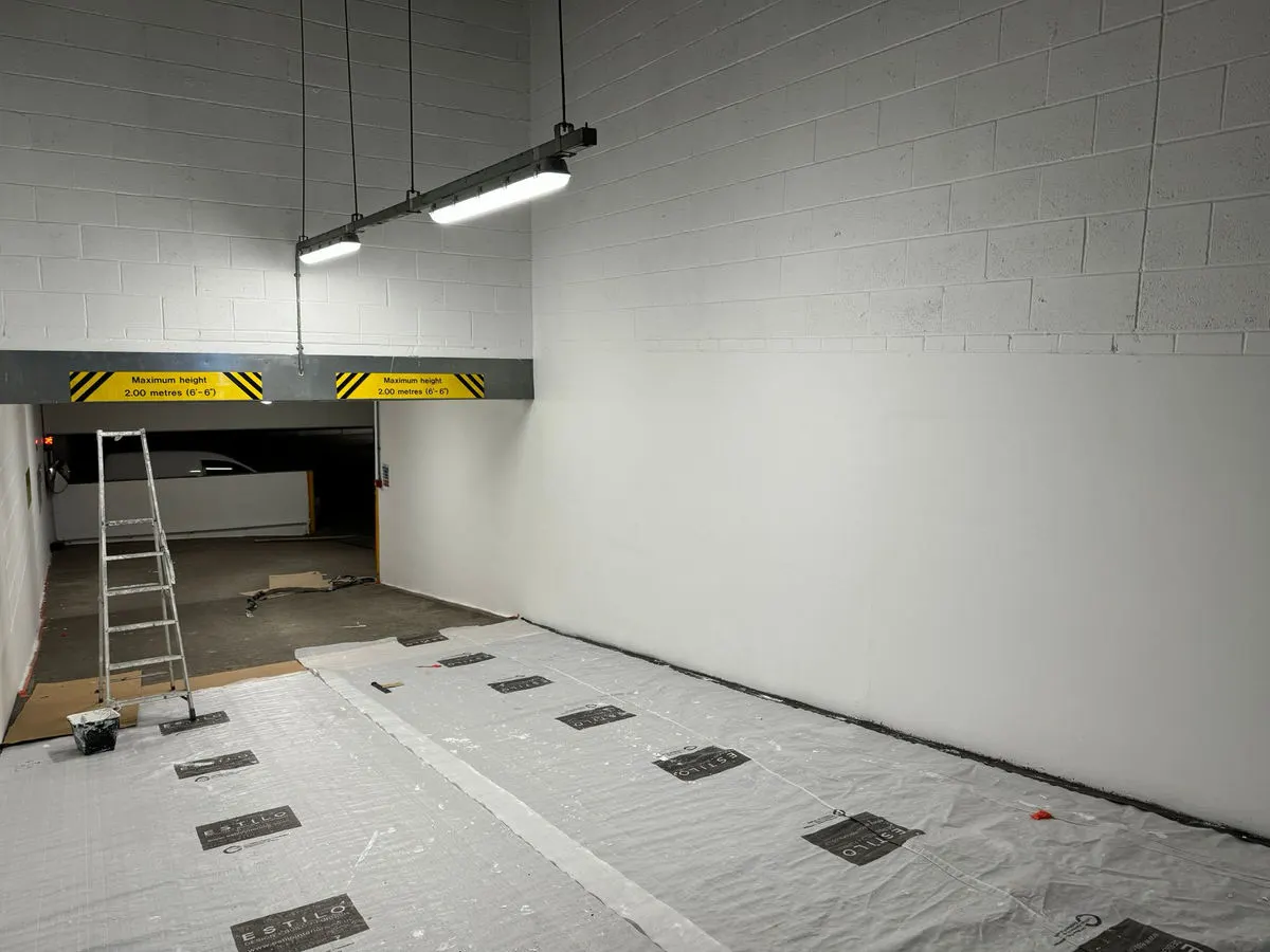 Underground car park area with freshly painted white blockwork walls and protective floor sheeting