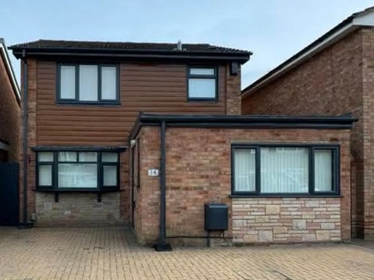 Detached house with anthracite grey sprayed UPVC windows and wood-effect cladding on upper storey